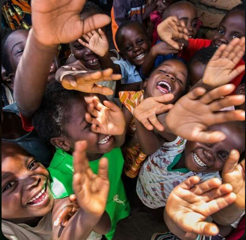 Children laughing and reaching toward the camera with joy